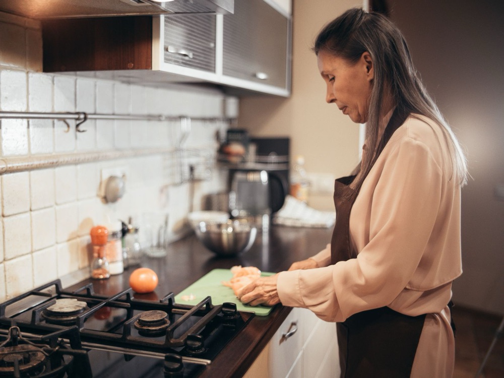 Mulher na casa dos 40 preparando uma refeição na cozinha de casa